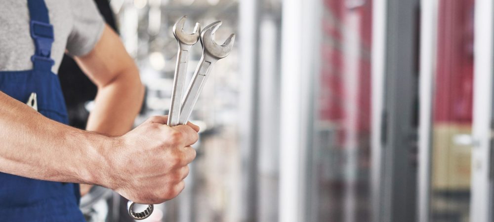 Hand of car mechanic with wrench. Auto repair garage.